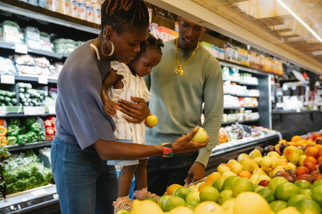 Young family choosing fresh fruits together in a supermarket aisle.